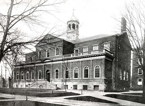 Black and white photo of brick building on college campus.