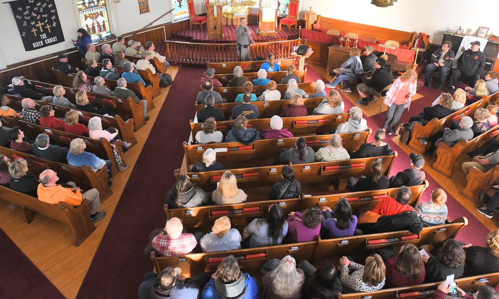 An overhead shot of many people sitting in church pews
