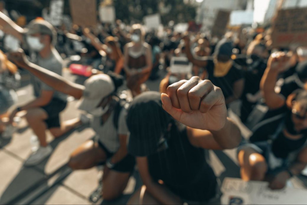 A group of people kneel while holding their fists in the air